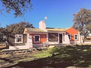 ein orangefarbenes und weißes Haus mit einem Rasenhof in der Unterkunft Monte dos Binos in Porto Covo