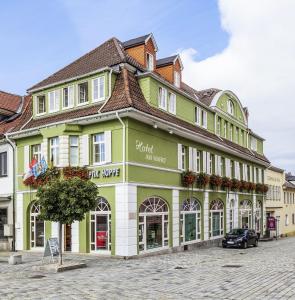 a green and white building on a street at Hotel Garni am Markt in Neustadt bei Coburg