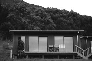 a small house with a table and chairs in front of a mountain at The Huts in Ahipara