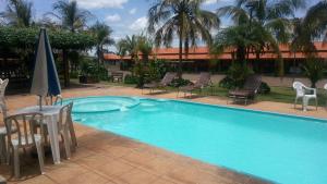 a large swimming pool with chairs and a table and umbrellas at Pousada Manna in Olímpia