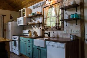 a kitchen with green cabinets and a white refrigerator at Heaven's Hideaway- perfect getaway near the river! in Luray