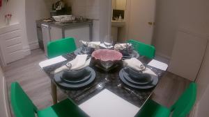 a dining room with a table and green chairs at London Queen Park Apartments in London