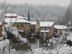 a village with snow covered buildings and a river at Il Borghetto Vacanze nei Mulini in Valeggio sul Mincio