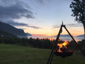un fuego en una hamaca con la puesta de sol en el fondo en House in the heart of the Lyngen Alps with Best view en Lyngseidet