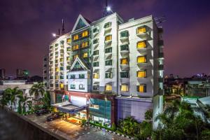 a tall white building at night with lights at Orchardz Jayakarta in Jakarta