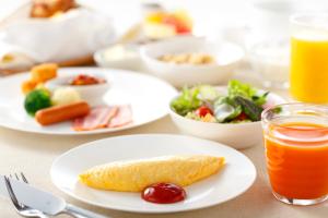 a table with plates of food and a glass of orange juice at Haneda Excel Hotel Tokyu Haneda Airport Terminal 2 in Tokyo