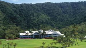a large house on a golf course with palm trees at Tranquility Chill at Palm Cove in Cairns
