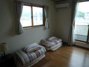2 Ottomanen in einem Zimmer mit Fenster in der Unterkunft Sea Side Hostel Light House in Onomichi