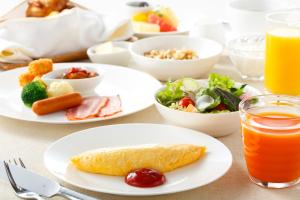 a table with plates of food and a salad and juice at Haneda Excel Hotel Tokyu Haneda Airport Terminal 2 in Tokyo
