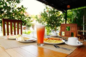a table with plates of food and a glass of beer at D'padang villa & Homestay in Uluwatu