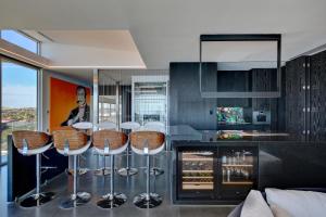 une cuisine avec un bar et des tabourets. dans l'établissement Luxe Haus, à Moana