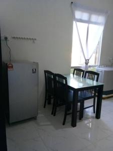 uma sala de jantar com uma mesa e cadeiras e um frigorífico em Penarik baru homestay em Kampung Penarik