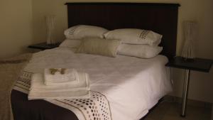 1 cama grande con sábanas y almohadas blancas en Coffee@Home (Pty) Ltd, en Prieska