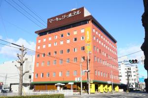 Un alto edificio rosso con un cartello sopra di Hotel 1-2-3 Maebashi Mercury a Maebashi