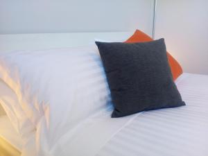 a white bed with an orange pillow on it at East 34 in Ballarat