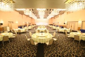 una grande sala banchetti con tavoli e sedie bianchi di Hotel 1-2-3 Maebashi Mercury a Maebashi