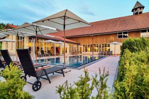 a pool with chairs and umbrellas next to a building at Wellness- und Vitalhotel Böhmhof in Bodenmais