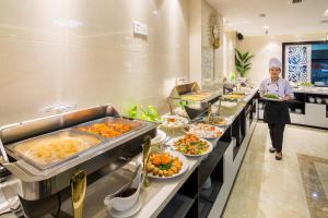 a woman standing in a buffet line of food at Dana Marina Boutique Hotel in Da Nang