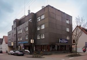 ein schwarzes Gebäude mit Autos, die davor geparkt sind. in der Unterkunft KONTAKTLOS Hotel Am Kappelberg KONTAKTLOS in Fellbach