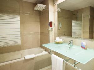 a bathroom with a sink and a tub and a mirror at Hotel MS Maestranza Málaga in Málaga