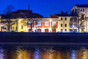 ヴェローナにあるRUBELE40の水面の横にオレンジ色の灯りが灯る建物