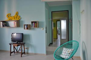 リミニにあるCasa Saraghinaのテレビ、椅子、廊下が備わる客室です。