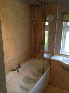 a bath tub with a shower and a sink at Comfortable House in Warwick in Warwick +6 photos
