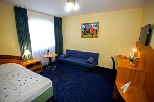 Habitación de hotel con cama y sofá azul en Hotel Savoy, en České Budějovice