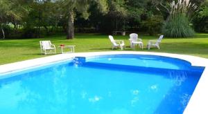 a blue swimming pool with chairs and a table at Chawasi Cabañas in Campo Quijano