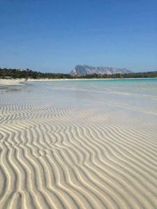 uma praia com ondulações na areia e na água em nonna antonietta em San Teodoro