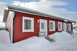 a red house with snow in front of it at Guesthouse Haltinmaa in Kilpisjärvi