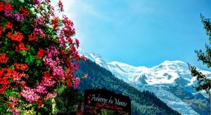 un cartello di fronte a una montagna con dei fiori di Auberge du Manoir a Chamonix-Mont-Blanc