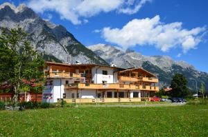 a building in front of mountains with a green field at Appartement Tirolia Leutasch in Leutasch