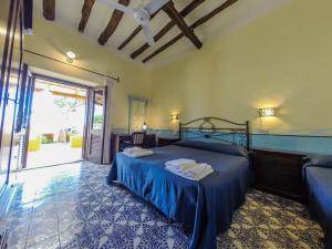 a bedroom with a bed with a blue bedspread at Hotel Arcangelo - Salina in Santa Marina Salina