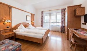 ヴァルダーオラにあるHotel Alp Cron Moarhofのベッドとデスクが備わるホテルルームです。