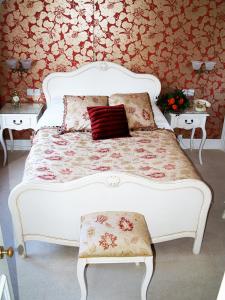 een wit bed met een rood kussen en 2 tafels bij Tower House 1066 in Hastings