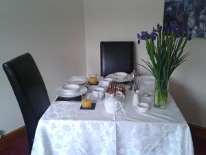 a table with a white table cloth and a vase of flowers at Manor Garden Lodge in Wirral