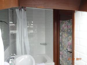y baño con ducha, lavabo y bañera. en La Casona de Villanueva de Colombres en Villanueva