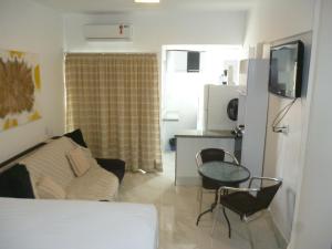 a bedroom with a bed and a table and a kitchen at Bahia Flat 117 in Salvador