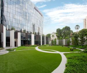 a green lawn in front of a building at Mercure Singapore On Stevens in Singapore