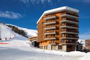a building in the snow next to a ski slope at Araucaria Hotel & Spa in La Plagne