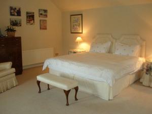 a bedroom with a large white bed and a chair at Courtyard Cottage in Carlow