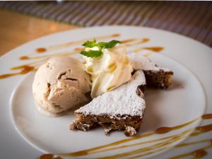 een witte plaat met een stuk cake en ijs bij Gasthaus Göscheneralp in Göschenen