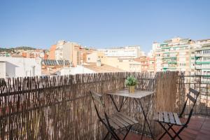 a table and two chairs on a balcony with a fence at Flateli Providencia in Barcelona