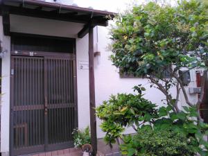 una puerta delantera de una casa con un árbol en Enman Guest House Osaka en Osaka