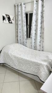 Cama en habitación con cortinas blancas en Apartamento dois quartos perto da praia em Jardim Camburi, en Vitória