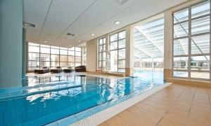 a large swimming pool in a building with windows at Diva Resort in Kołobrzeg