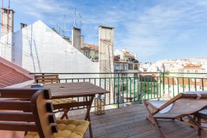 リスボンにあるBairrus Lisbon Apartments - Principe Real/Brickの木製テーブルと椅子付きのバルコニーが備わる客室です。