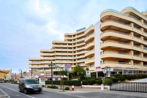 a truck driving past a large apartment building at Apartamento MarinaMar in Vilamoura