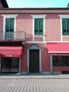 a pink building with red awnings on a street at Casa Ternavassi in Carmagnola